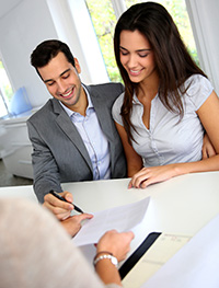 this is a picture of a couple signing papers